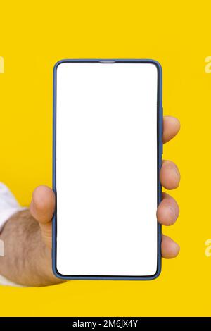 Close up man hand holding smartphone with white blank screen and blue phone case. Isolated on yellow background. Mobile phone fr Stock Photo