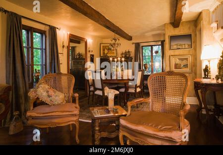 Antique wooden grid high back armchairs in living room looking towards dining room inside old 1809 cottage style home. Stock Photo