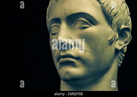 Bronze color gypsum copy of ancient statue of Germanicus Julius Caesar head for artists on black background. Renaissance epoch. Stock Photo