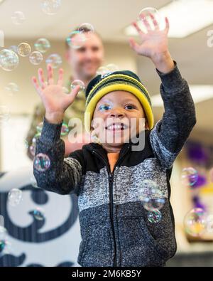 A child plays with bubbles at Wright Field South child development center, April 29, 2022, at Wright Patterson Air Force Base, Ohio. Children were celebrated with the bubbles, music and the opportunity to walk the purple carpet in honor of the Month of the Military Child. 88 ABW,88th Air Base Wing,Wright-Patterson Air Force Base, Stock Photo