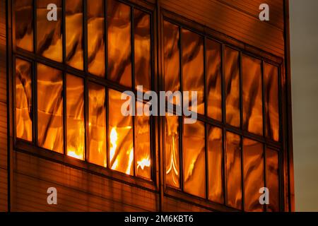 The glass and iron facade of huge skyscraper at sunset, steel, orange color, reflection of sun Stock Photo