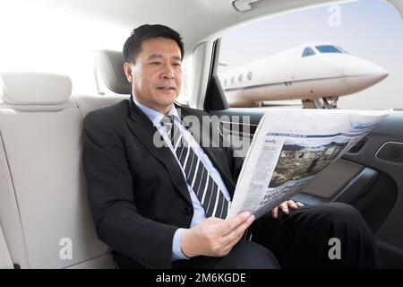 Business man reading a newspaper in the sitting car Stock Photo