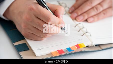 Hands of a businessman writing a schedule or recording ideas in a diary Stock Photo