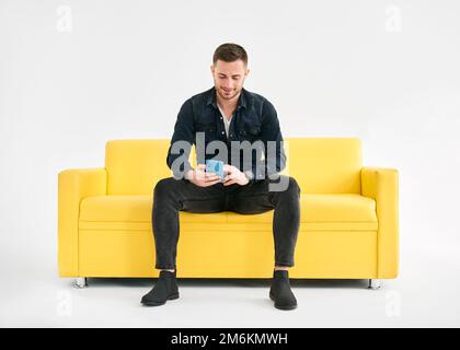 Relaxed man sitting on couch using hsi mobile smart phone Stock Photo