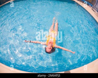 Woman in yellow swimming suit in clear blue water in pool Stock Photo