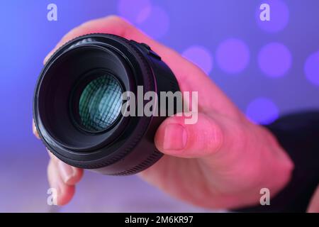 chinese 50mm lens in hand over table and colored background Stock Photo