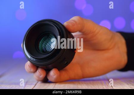 chinese 50 mm lens in hand on table and colored background Stock Photo