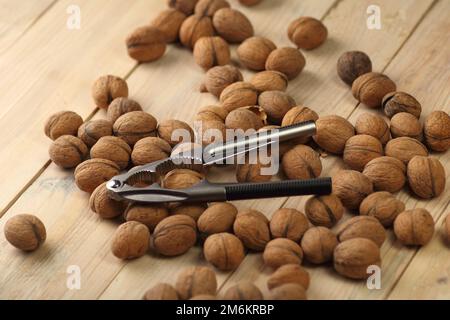 metal nutcracker on a wooden table with nuts Stock Photo