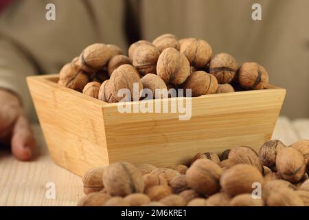 walnuts in a wooden case on the table and the background of the person Stock Photo