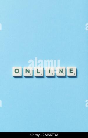 Online formed of scrabble blocks on blue background. Stock Photo