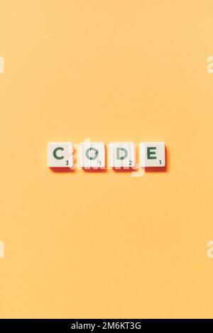 Code formed of scrabble blocks on yellow background. Stock Photo