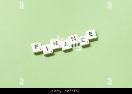 Finance formed of scrabble blocks on green background. Stock Photo