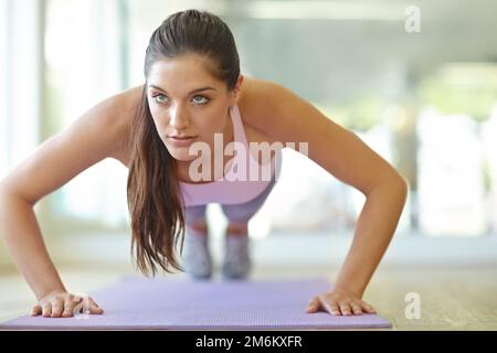 Focused on her push-ups. A beautiful young woman doing push-ups. Stock Photo