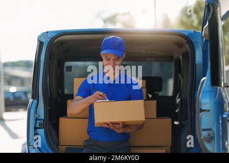 Asian courier with parcel and delivery logistic concept. Delivery man using digital tablet Stock Photo