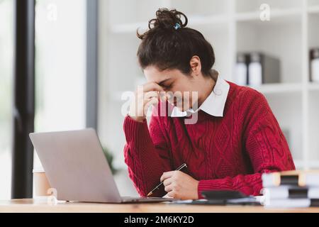 American Woman looking stressed while using laptop with financial document on table. Woman work from home Stock Photo