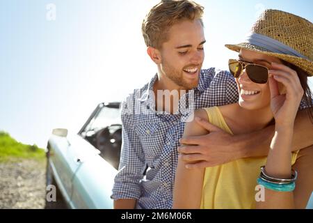 Youre more beautiful that the view...A happy young couple standing next to their convertible parked by the side of the ocean. Stock Photo