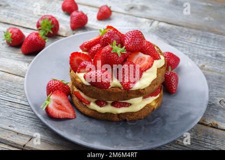 Traditional roasted Italian panettone tiramisu with vanilla custard curd and strawberries served as close-up in a design plate Stock Photo