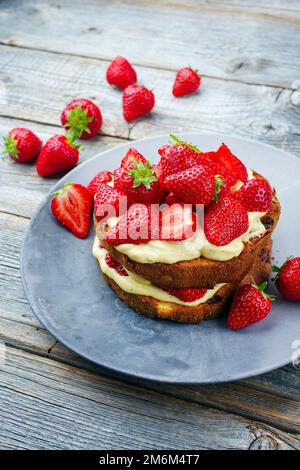 Traditional roasted Italian panettone tiramisu with vanilla custard curd and strawberries served as close-up in a design plate Stock Photo