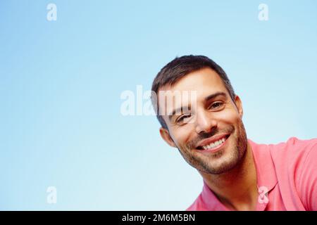 Hey down there. Low angle portrait of a handsome young man against a blue sky. Stock Photo