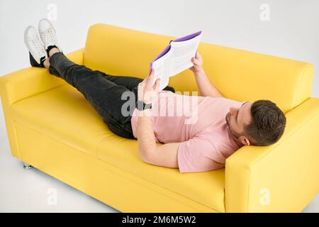 Man relaxing on sofa reading book Stock Photo