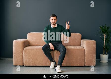 Trendy man showing hand gesture V sign for victory or peace looking ro camera Stock Photo
