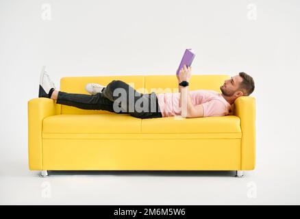 Man relaxing on sofa reading book Stock Photo