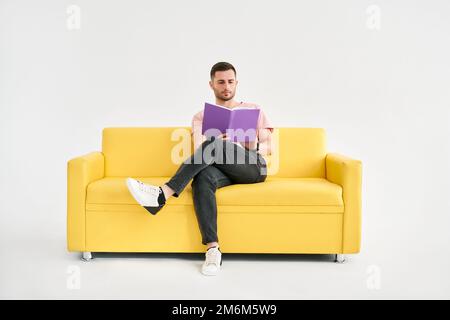 Man relaxing on sofa reading book Stock Photo