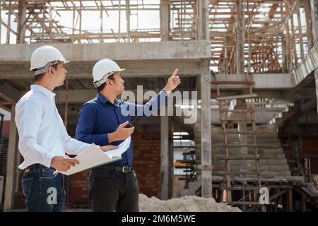 Construction engineer inspecting and working outdoors structure building site with blueprints. Stock Photo