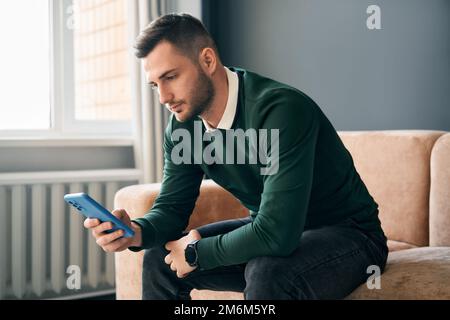 Relaxed man sitting on couch using hsi mobile smart phone Stock Photo