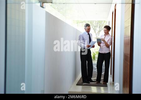 Old school versus new school. Two office workers discussing the convenience of having a digital tablet. Stock Photo