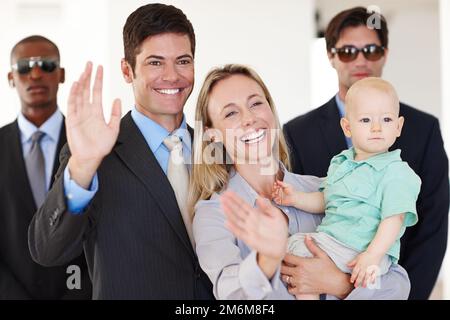 The public loves them. a politician and his family waving at a public event with bodyguards protecting them. Stock Photo