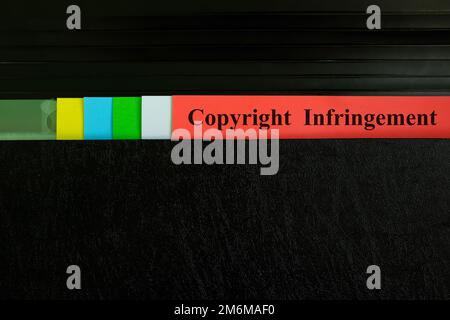 Hand picking copyright infringement file record in black binder folder. Copyright violation business legal concept. Stock Photo
