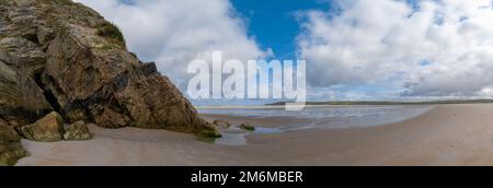 A panorama landscape view of Maghera Beach with the entrance to one of the caves in the rocks Stock Photo