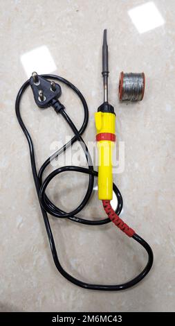 an electric soldering tool with plug and solder metal wire on the floor used by students and electricians in the lab Stock Photo
