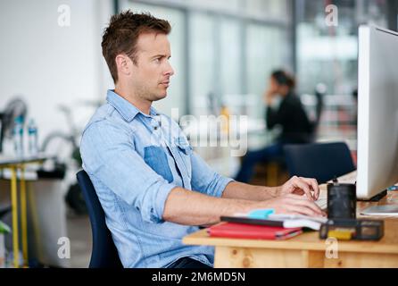 Design online. a handsome young man working at his desk in an office. Stock Photo