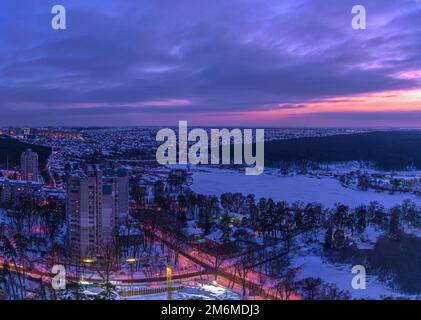 Sunset over the outskirts of the city of Kyiv and snow-covered forest in winter. Kyiv, Ukraine Stock Photo