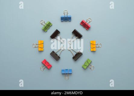 Circle of colorful binder clips against a light blue background Stock Photo