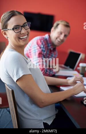 Working here is a blast. Cropped portrait of two young colleagues sitting in a boardroom. Stock Photo