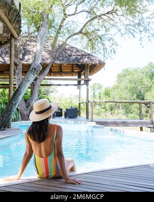Couple men and women on safari in South Africa relaxing by the pool of a luxury safari lodge , Stock Photo