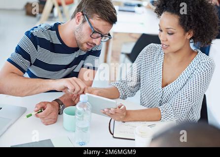 Young innovators. coworkers talking over a digital tablet. Stock Photo