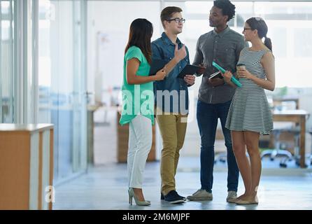 Getting down to business in the office. a diverse group of colleagues talking together while standing in an office. Stock Photo