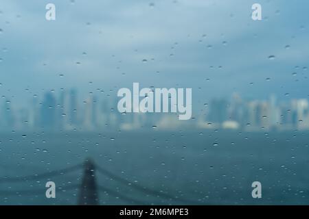 Rain drops on the glass of the car with modern Doha city skyline background. Selective focus Stock Photo