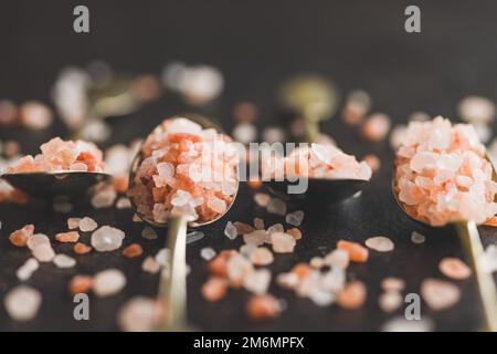 Pink himalayan salt in spoon on the black table. Stock Photo