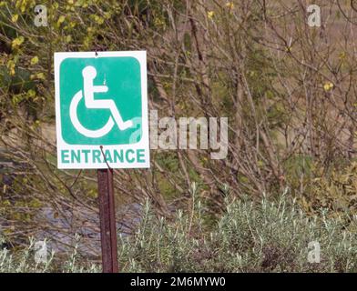 Weathered sign showing entrance for disabled persons on a wheelchair Stock Photo