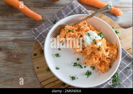 Carrot salad with yogurt dressing on wooden table with space for text Stock Photo