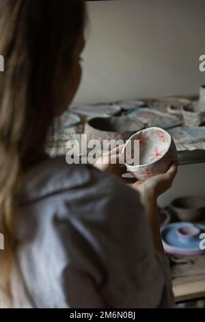 a girl from the back looks at a clay product, vertical frame, without a face Stock Photo