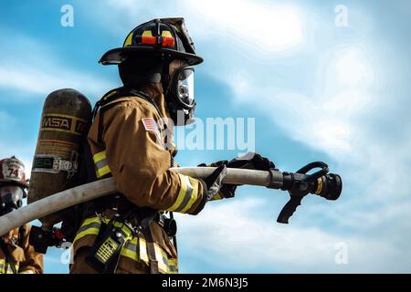 A 316th Civil Engineer Squadron firefighter prepares a water hose for use during an interagency fire-fight training at Joint Base Andrews, Md., May 2, 2022. During the exercise, 24 firefighters were split into multiple teams, with one team  at a time extinguishing fires and the remaining teams on standby. Stock Photo