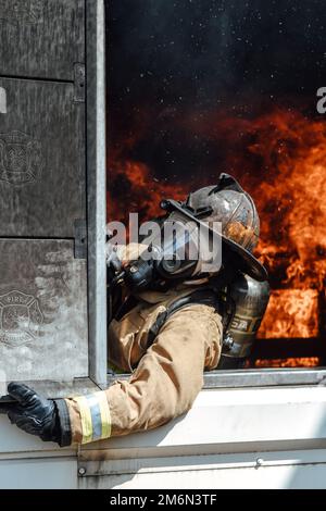 A 316th Civil Engineer Squadron firefighter shuts a window during a simulated building fire while participating inan interagency fire-fight training at Joint Base Andrews, Md., May 2, 2022. The team trained in a live-burn exercise to practice firefighting techniques and procedures in a realistic environment, ensuring they are prepared to mitigate damage and save lives. Stock Photo