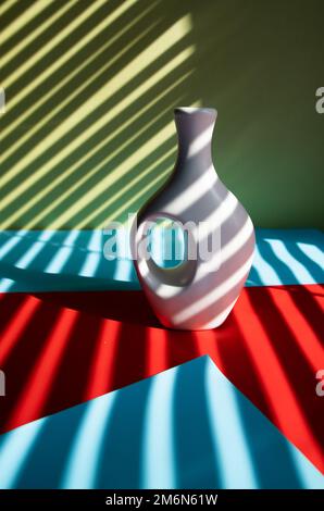 White vase and white flower on abstract striped multicolor background Stock Photo