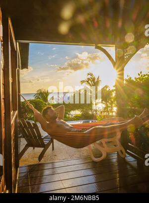 Young men in swim short with a coconut drink on a tropical beach La